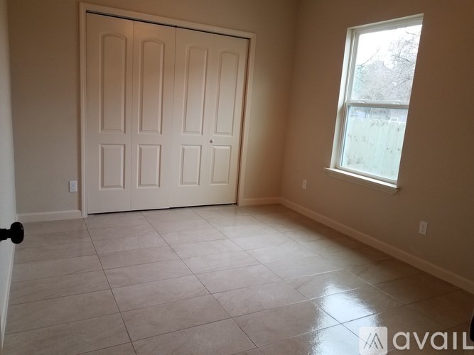 A room with a white door and a window with a view of a tree.