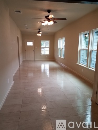 A spacious room with a ceiling fan and tiled flooring.