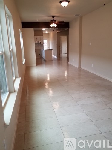 A long hallway with a tiled floor and a fan on the ceiling.