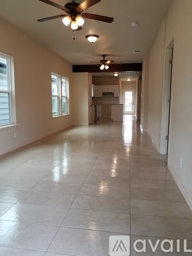 A long hallway with a ceiling fan and tiled flooring.
