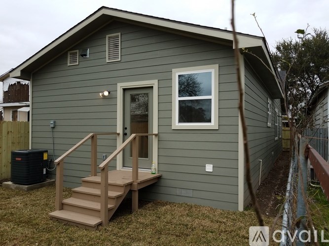 A small house with a grey siding and a white window.