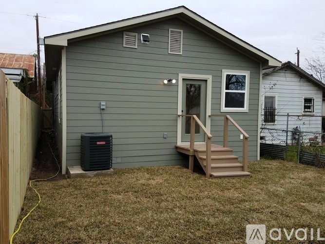 A grey house with a wooden deck and a black air conditioning unit.