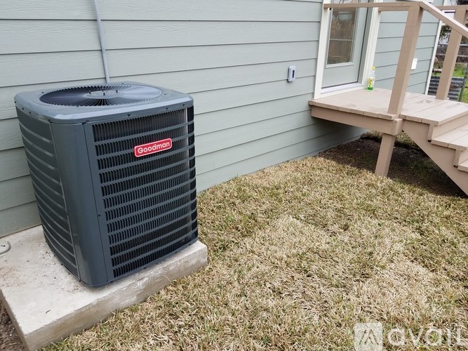 A Goodyear air conditioner unit sits on a concrete slab outside a house.