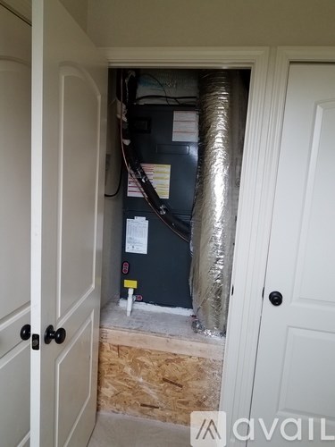 A room with a door and a wall with pipes and wires.
