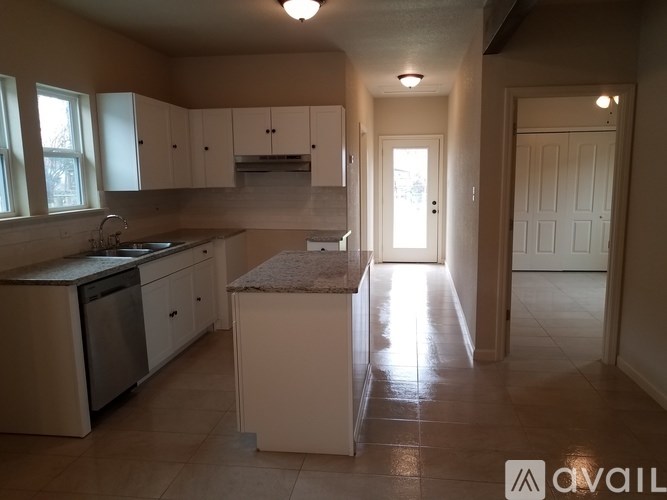A kitchen with white cabinets and a marble island.