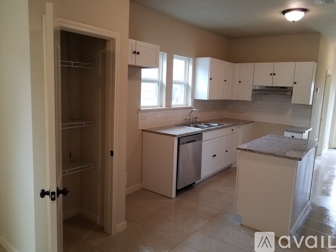 A kitchen with white cabinets and a granite countertop.