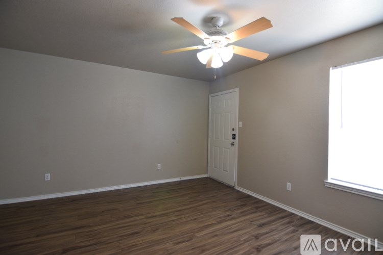 A room with a ceiling fan and wooden flooring.