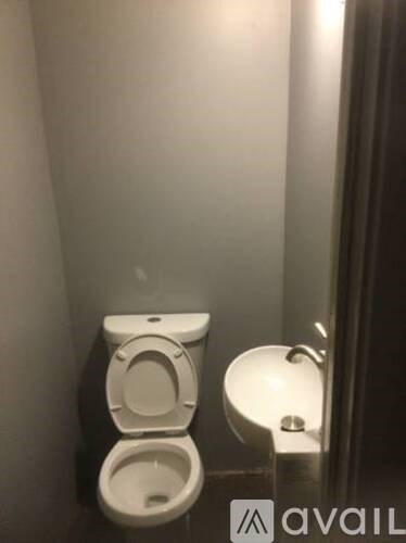 A white toilet with a bidet attachment is in a small bathroom.