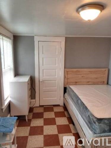 A bedroom with a bed, dresser, and window.