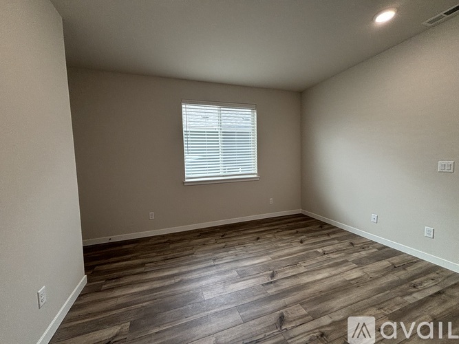 A room with wooden flooring and a window with blinds.