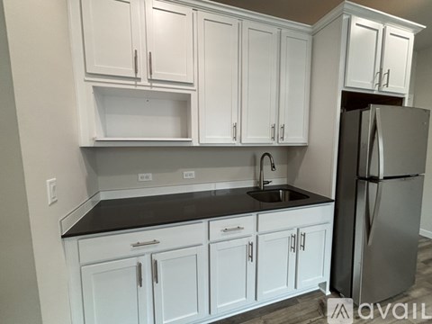 A kitchen with white cabinets and a black countertop.
