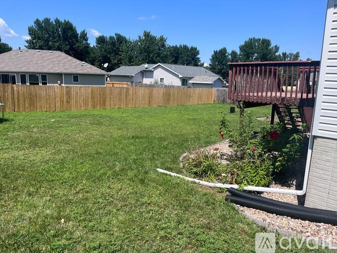 A backyard with a wooden fence and a deck.
