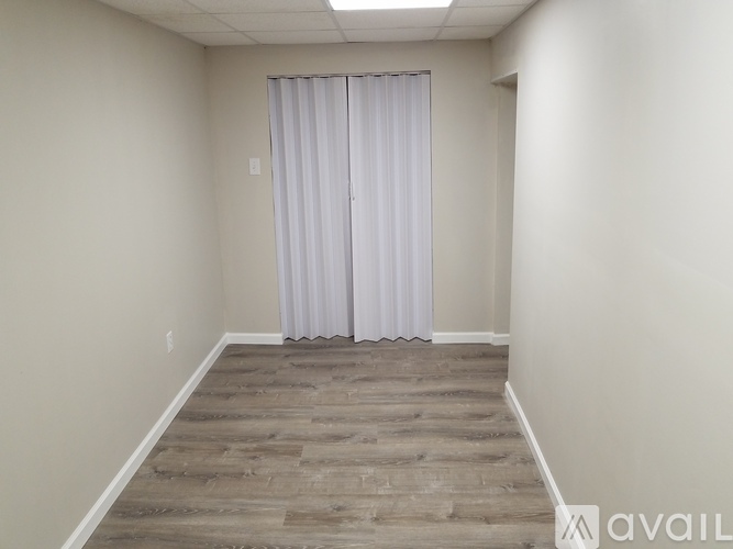 A room with a wooden floor and a white curtain.