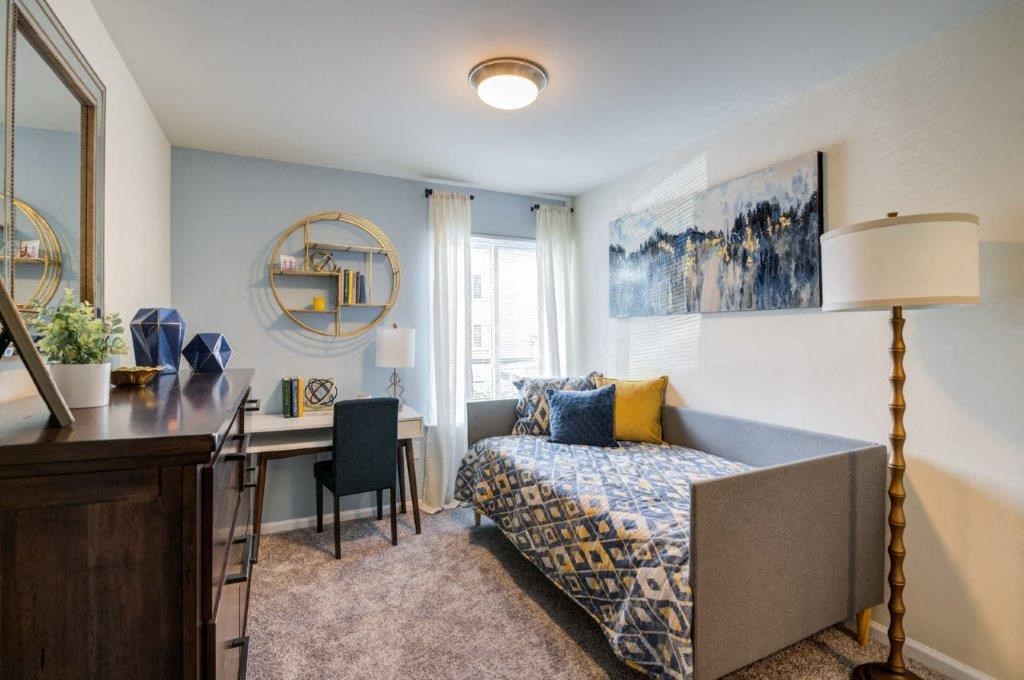 a living room with a couch and a desk and a window