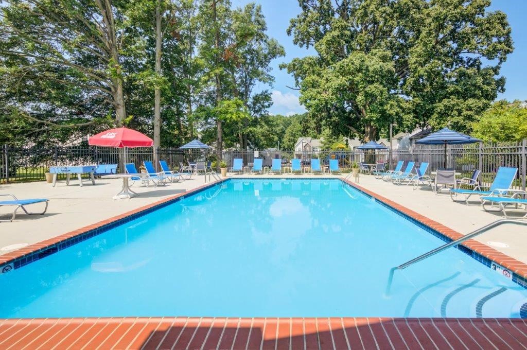 a swimming pool with chairs and tables around it