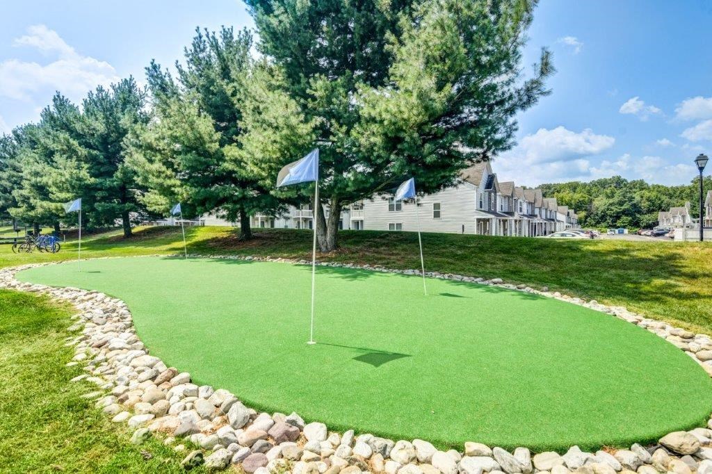 a putting green with two flags on it in front of a house