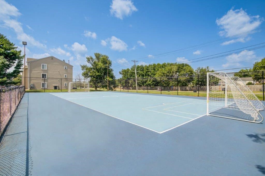 the tennis court is equipped with a net and a house in the background