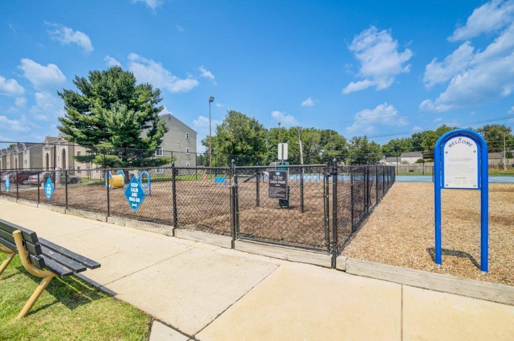 a fenced in dog park with a playground and a bench