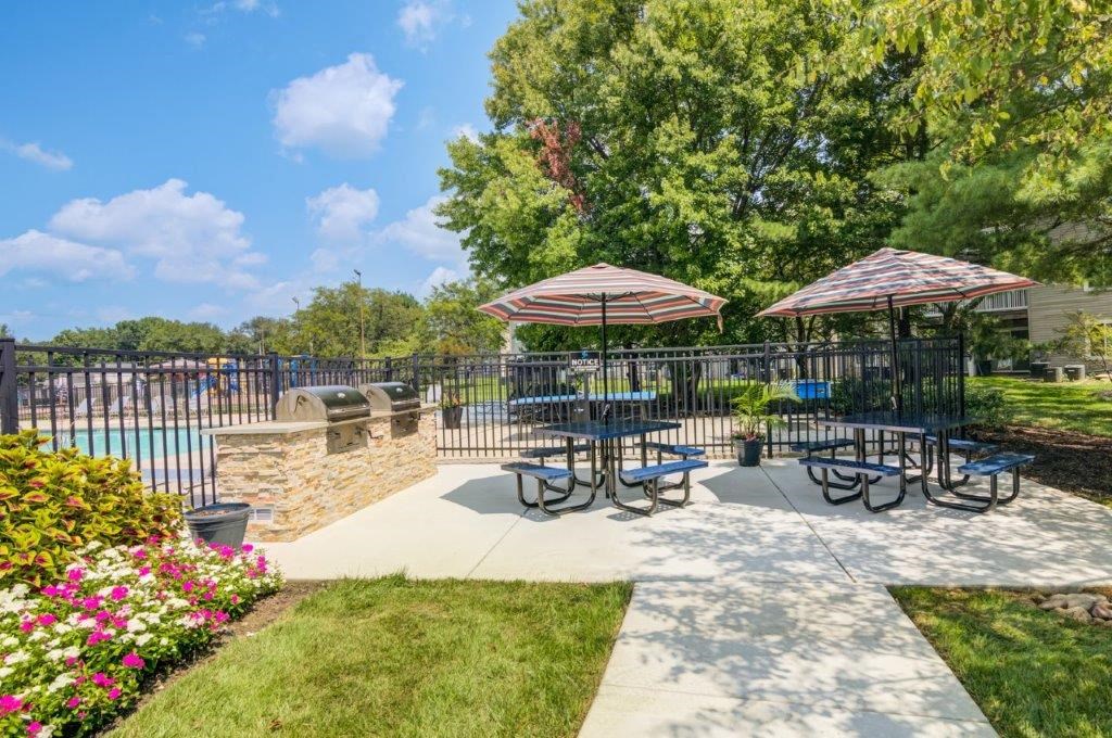 a patio with tables and umbrellas next to a swimming pool