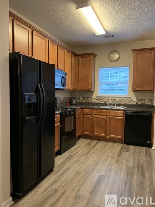 A kitchen with wooden cabinets and a black fridge.