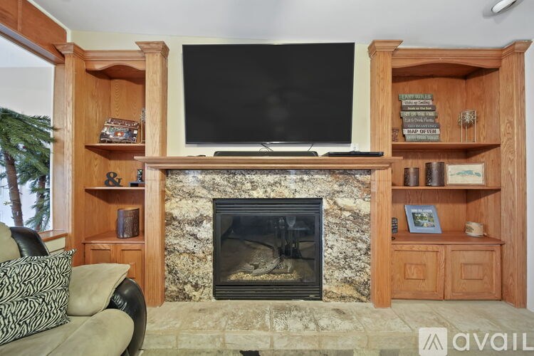A living room with a fireplace and a television mounted above it.