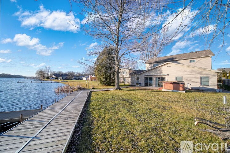A house is situated by a body of water with a dock leading to it.