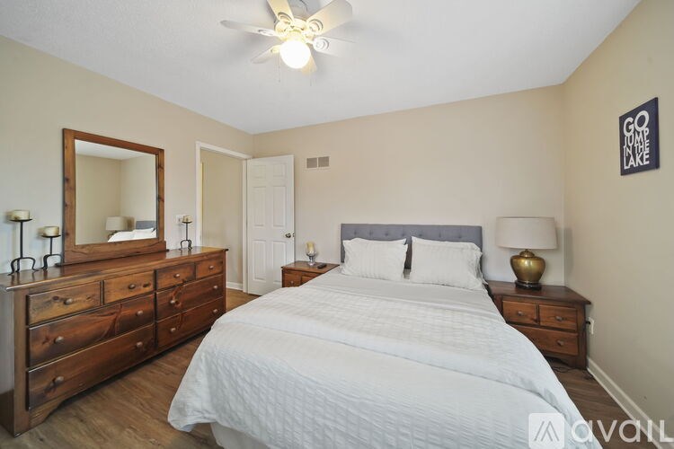 A bedroom with a large bed, a dresser with a mirror, and a lamp on the nightstand.