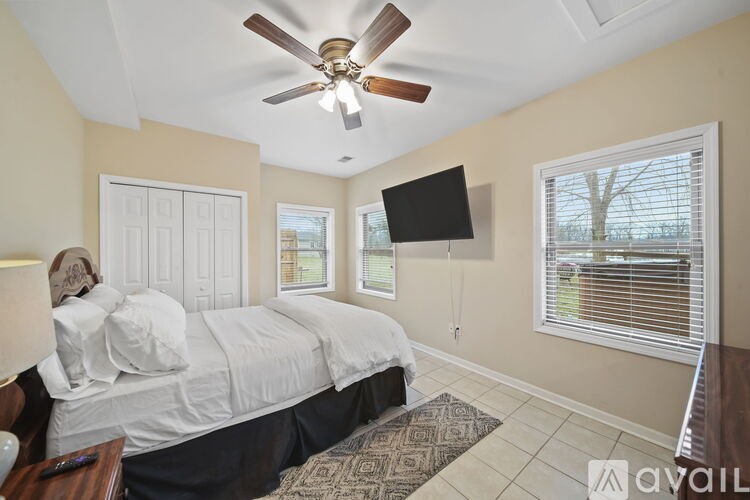 A bedroom with a bed, a ceiling fan, and a window with blinds.
