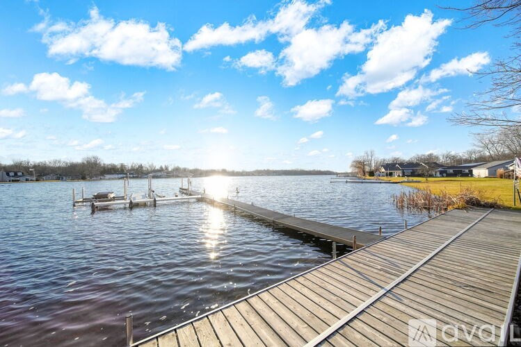 A serene lake with a wooden dock and a clear blue sky.