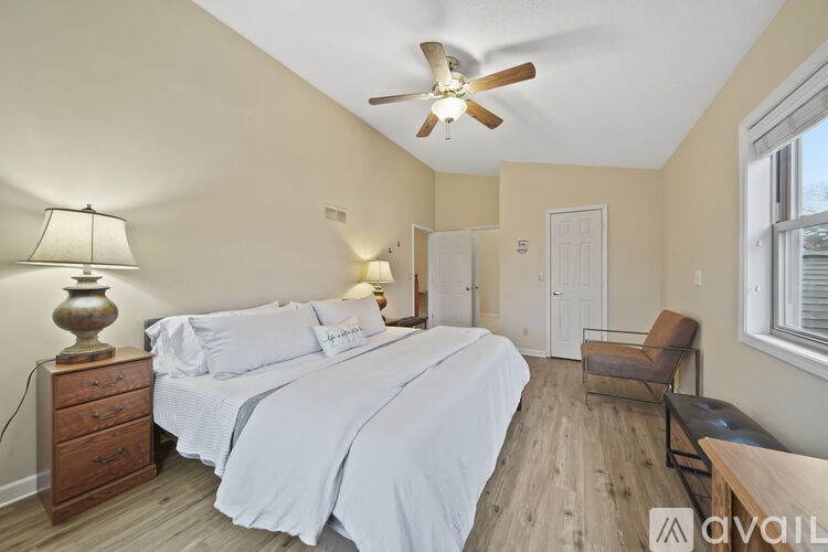 A bedroom with a bed, chair, and a ceiling fan.