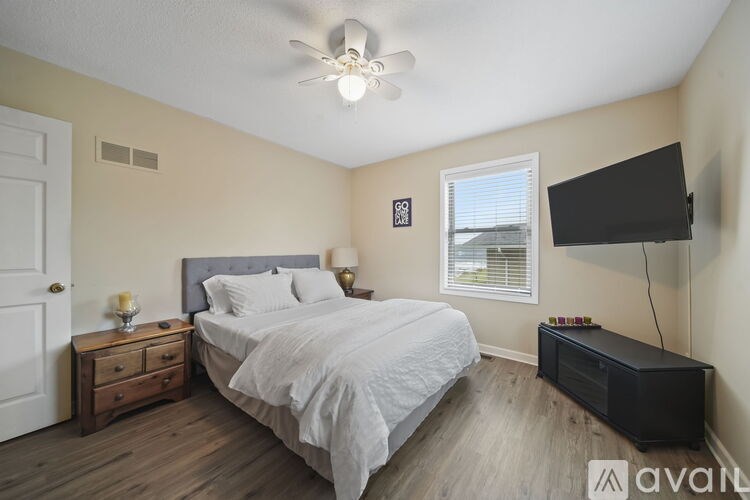 A bedroom with a bed, nightstand, and a flat screen TV mounted on the wall.