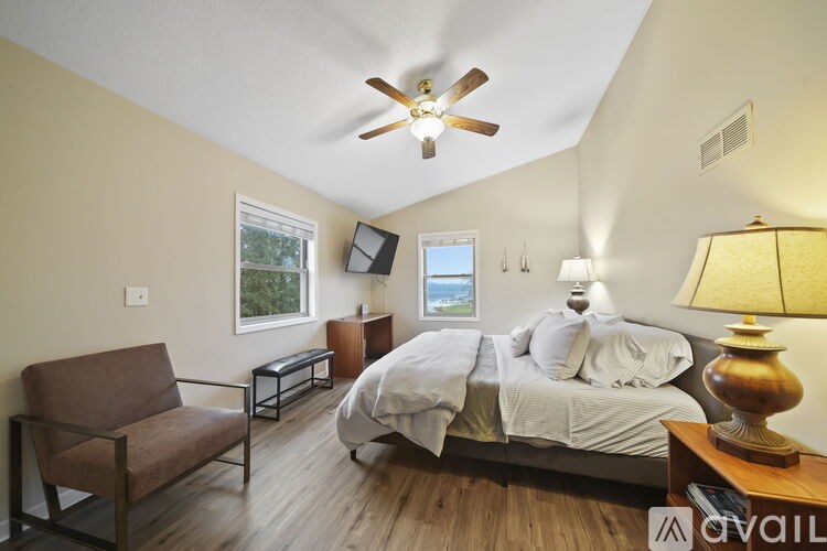 A bedroom with a bed, chair, and a ceiling fan.