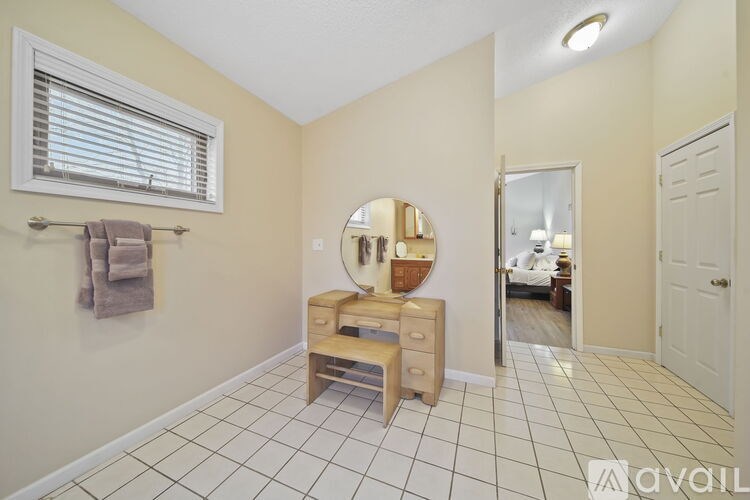 A bathroom with a vanity, mirror, and a towel hanging on the wall.