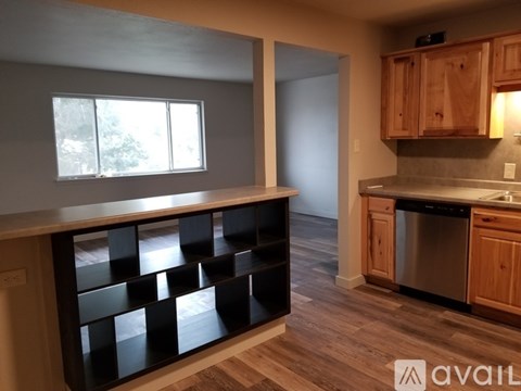 A kitchen with wooden cabinets and a black shelf unit.