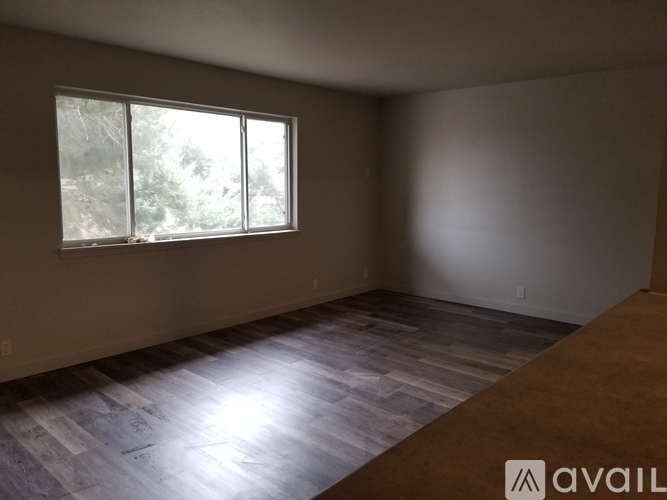 A room with a large window and wooden flooring.