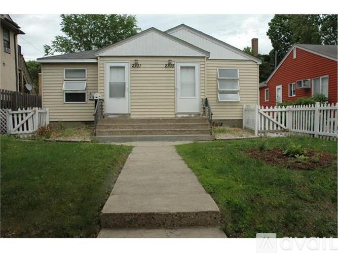 A small house with a white door and a concrete walkway leading to it.