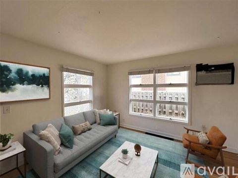 A living room with a grey couch, a small table, and a painting on the wall.