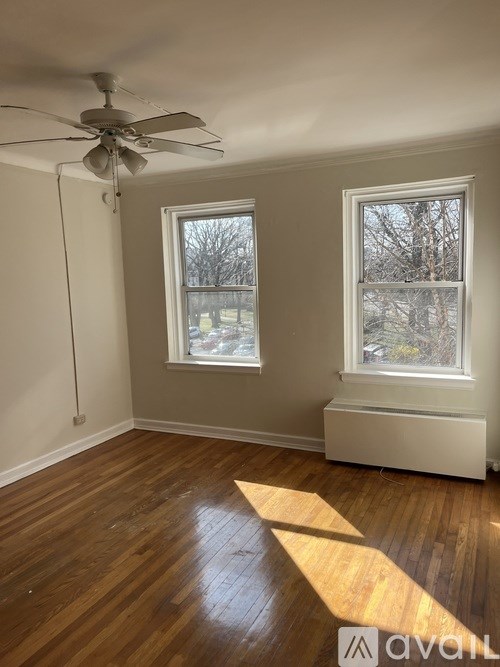 A room with a ceiling fan and two windows.