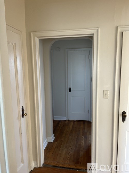 A white door with a black handle is in a hallway.