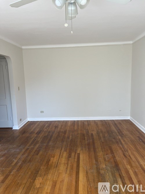 A room with wooden flooring and a ceiling fan.