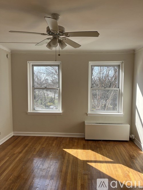 A room with a ceiling fan and two windows.