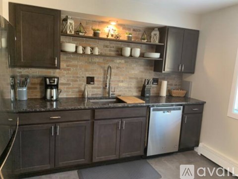 A kitchen with dark brown cabinets and a brick backsplash.