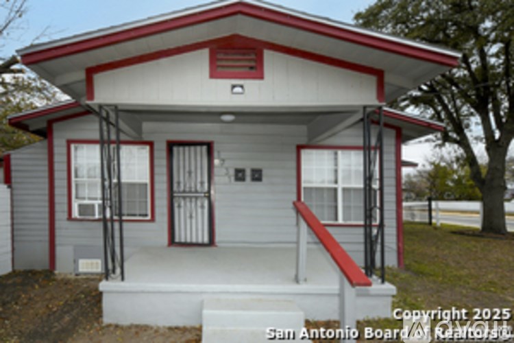 A small white and red house with a porch.