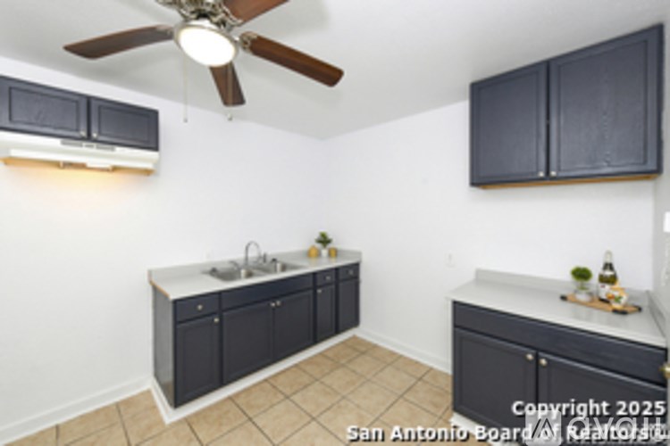 A kitchen with black cabinets and a ceiling fan.