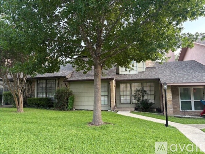 A tree stands in front of a house with a lawn.