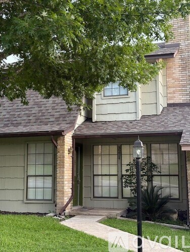 A house with a green lawn and a tree in front.