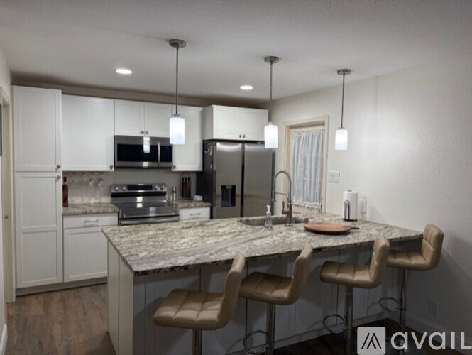 A kitchen with a marble countertop and bar stools.