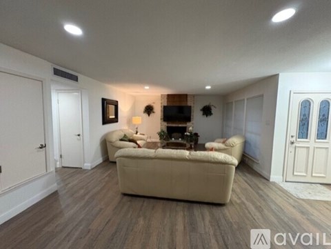 A living room with a beige couch and a flat screen TV mounted on the wall.