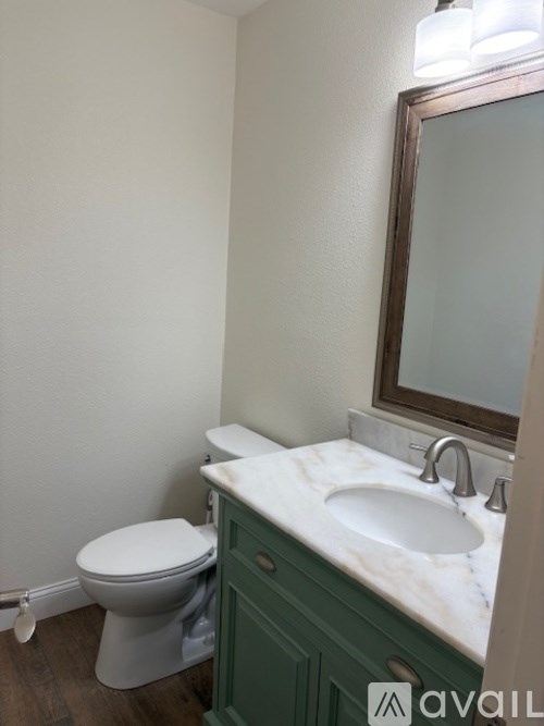 A bathroom with a toilet, sink and mirror.