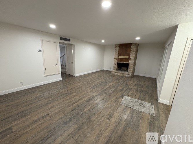 A spacious room with wooden flooring and a fireplace.